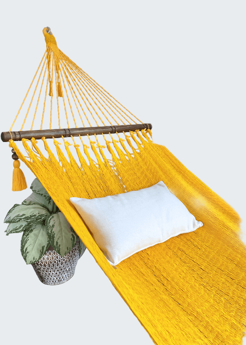 Yellow hammock with a white pillow on a neutral background