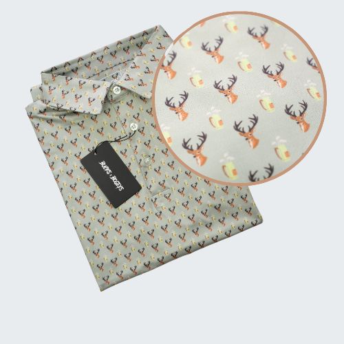 Folded shirt with a pattern of deer heads and antlers on a light green background, with a close-up inset showing the pattern.