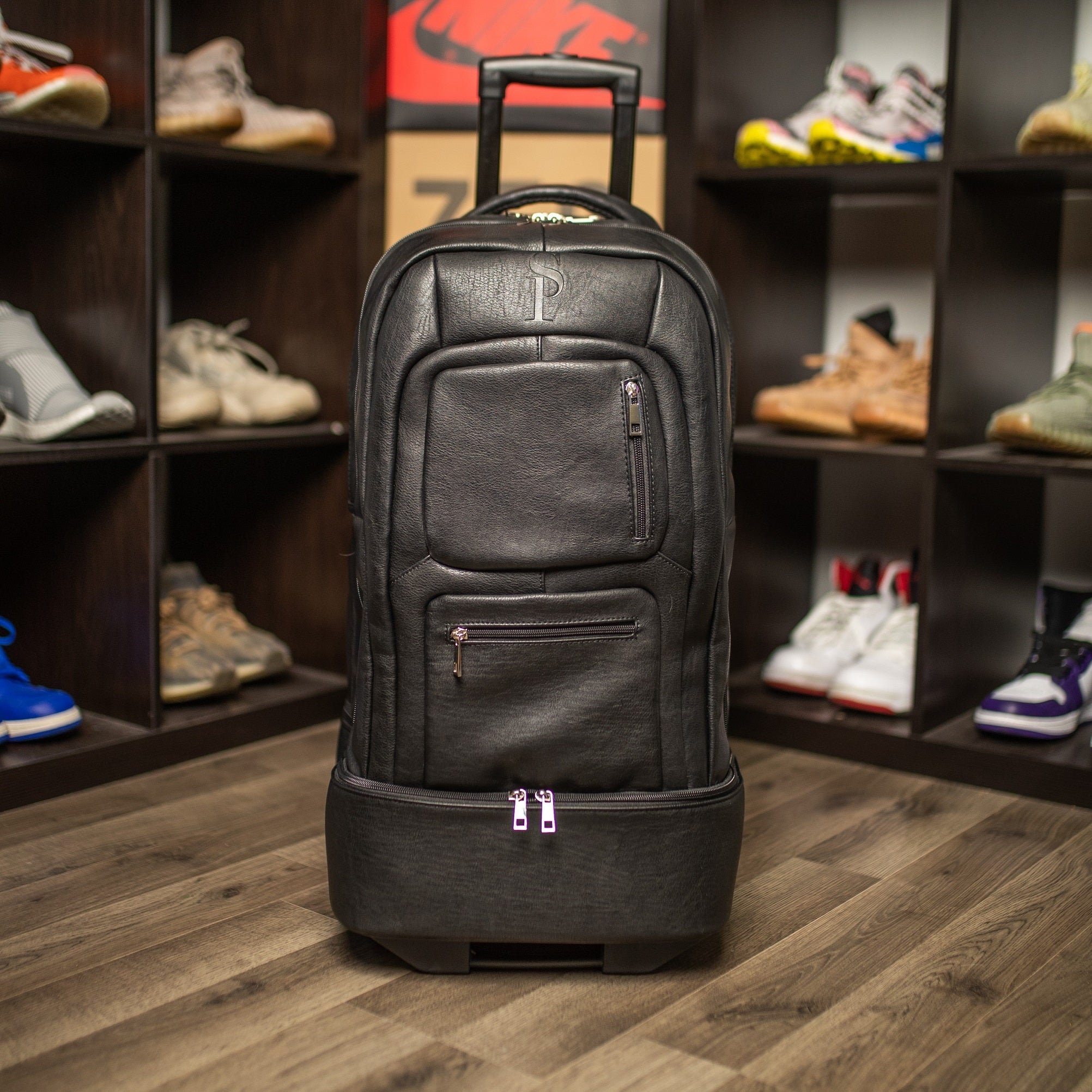 Black rolling backpack in a shoe store with shelves of shoes in the background