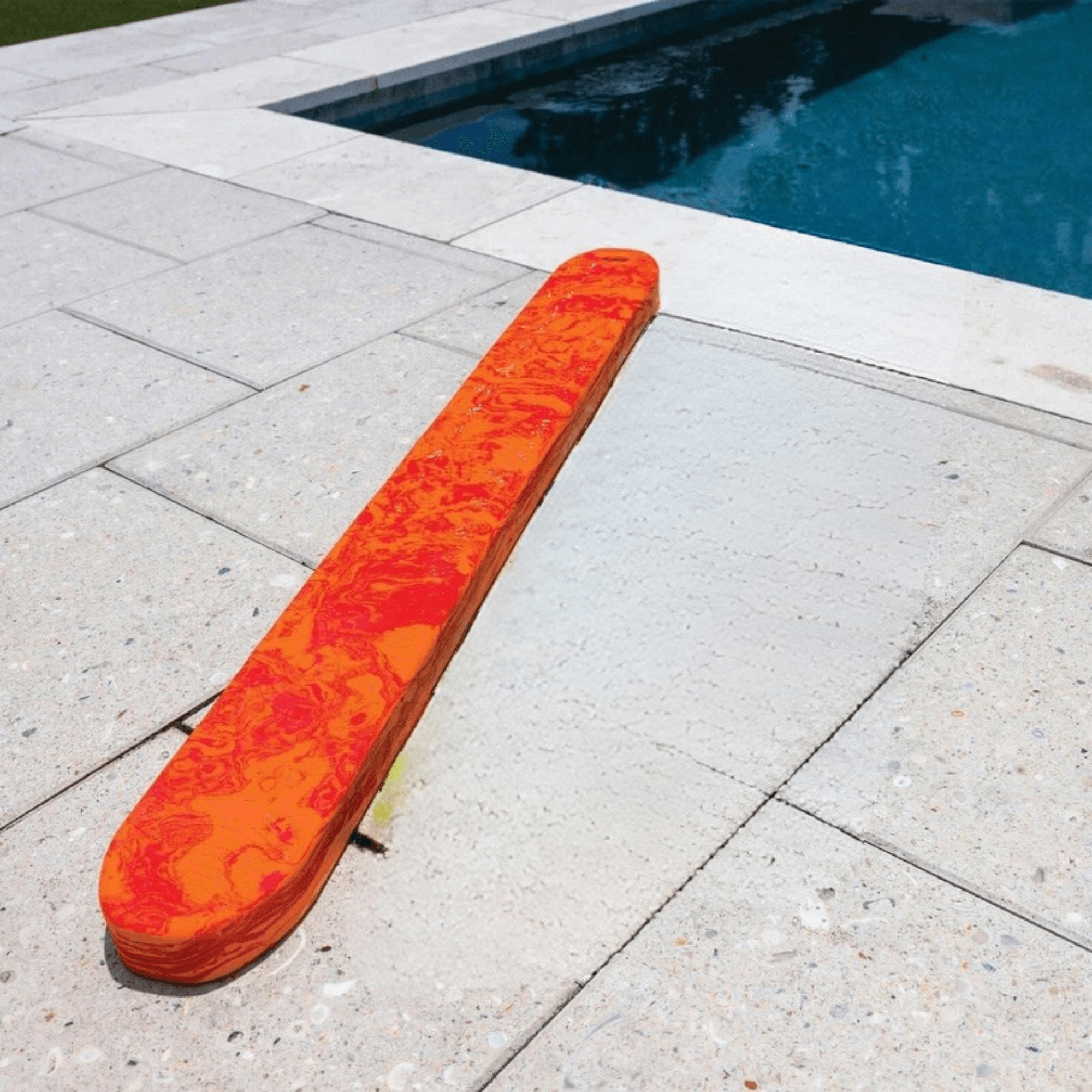 Orange diving board on a tiled pool deck