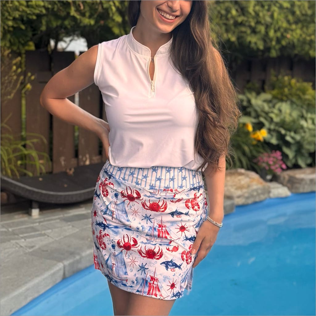 Woman wearing a white top and crab-patterned skirt by a pool