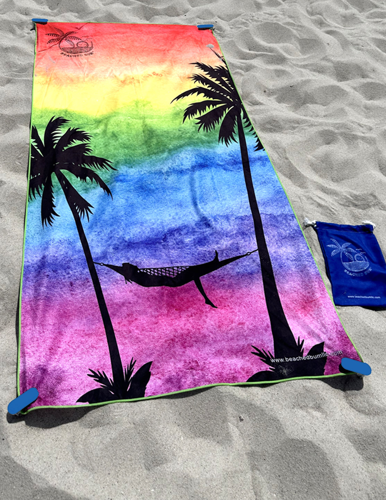 Colorful towel with palm tree and hammock design on a sandy surface