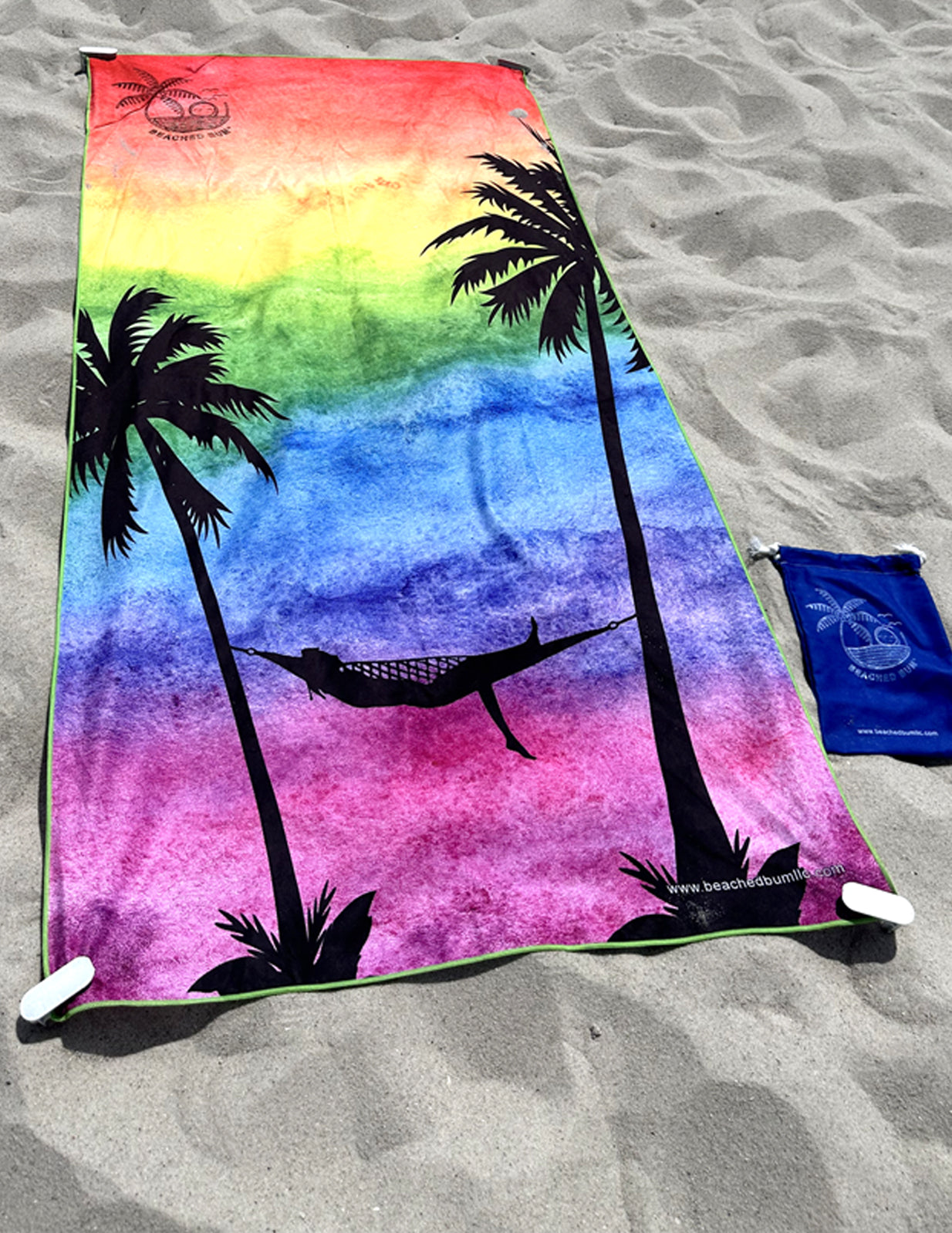 Colorful towel with palm tree and hammock design on a sandy surface