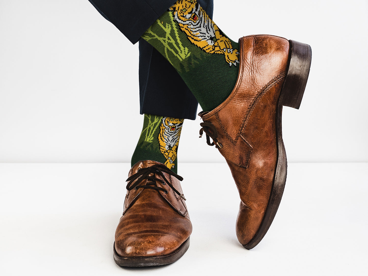 Brown leather shoes with tiger-themed socks on a white background