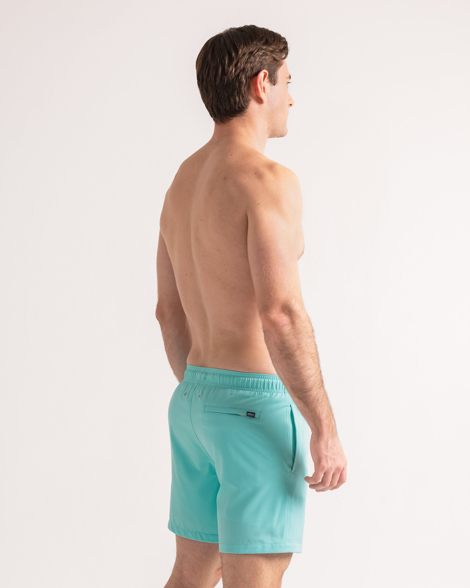 Man wearing turquoise swim shorts on a white background