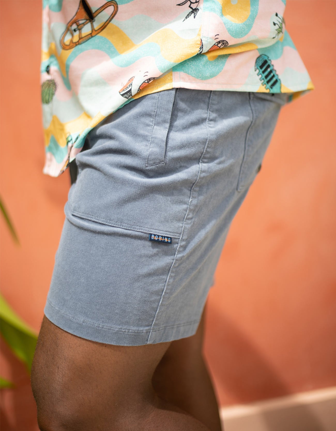 Person wearing light blue shorts with a colorful shirt in the background