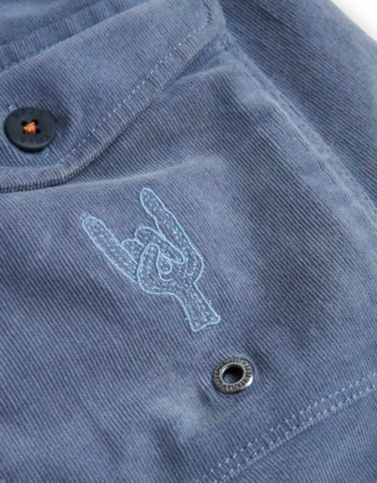 Close-up of a blue shirt with a logo and button details