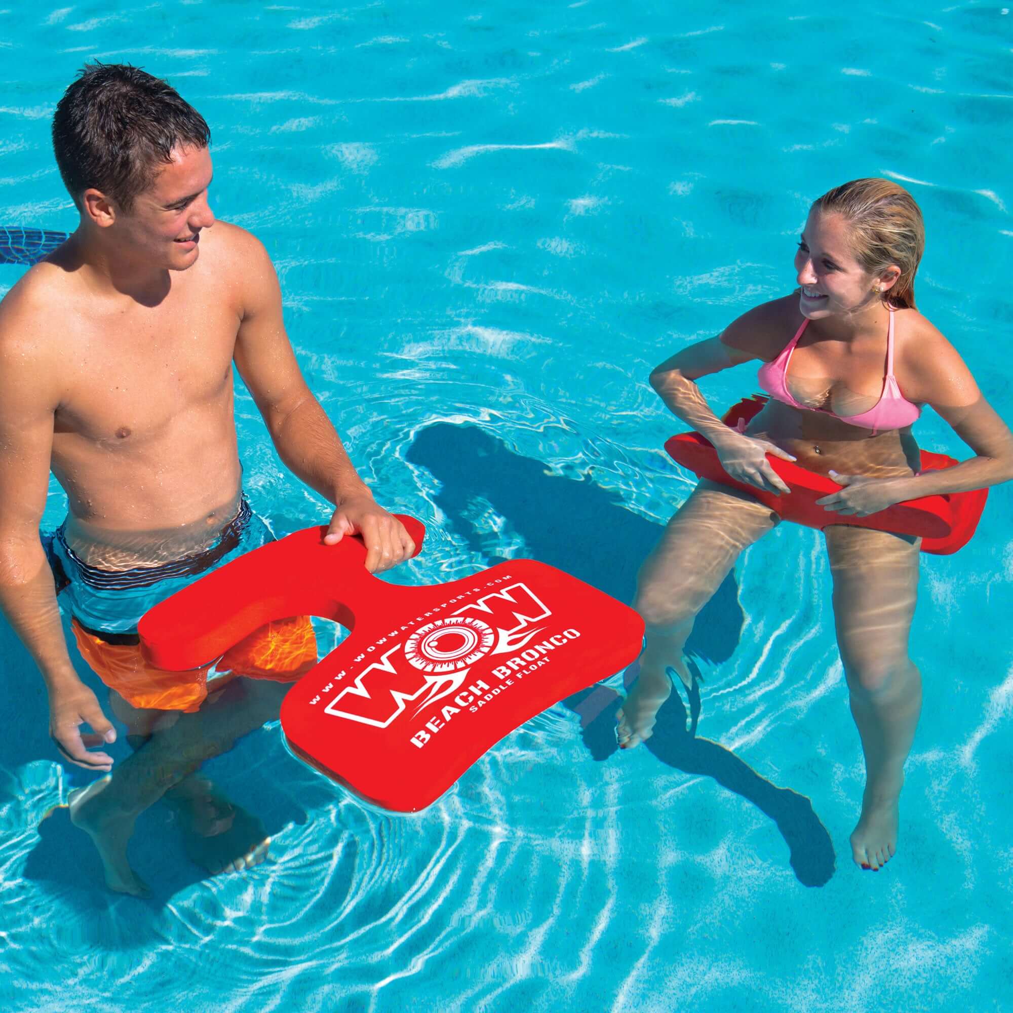 Two people in a pool holding red swim accessories with a visible brand logo.