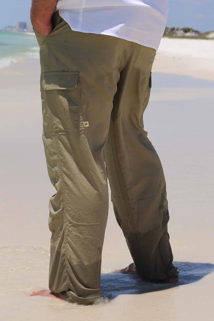 Person wearing olive green cargo pants on a sandy beach.