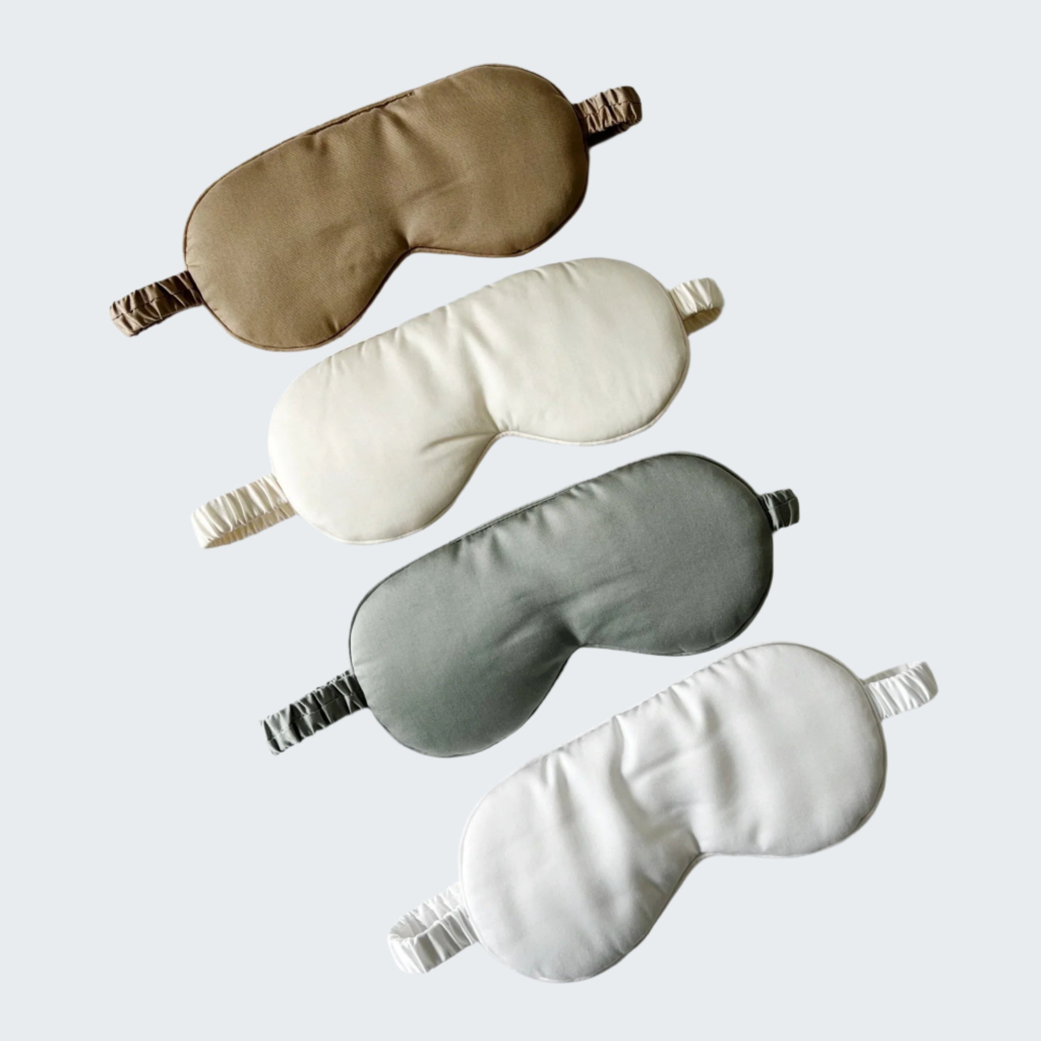 Four sleep masks in beige, white, gray, and white on a light gray background