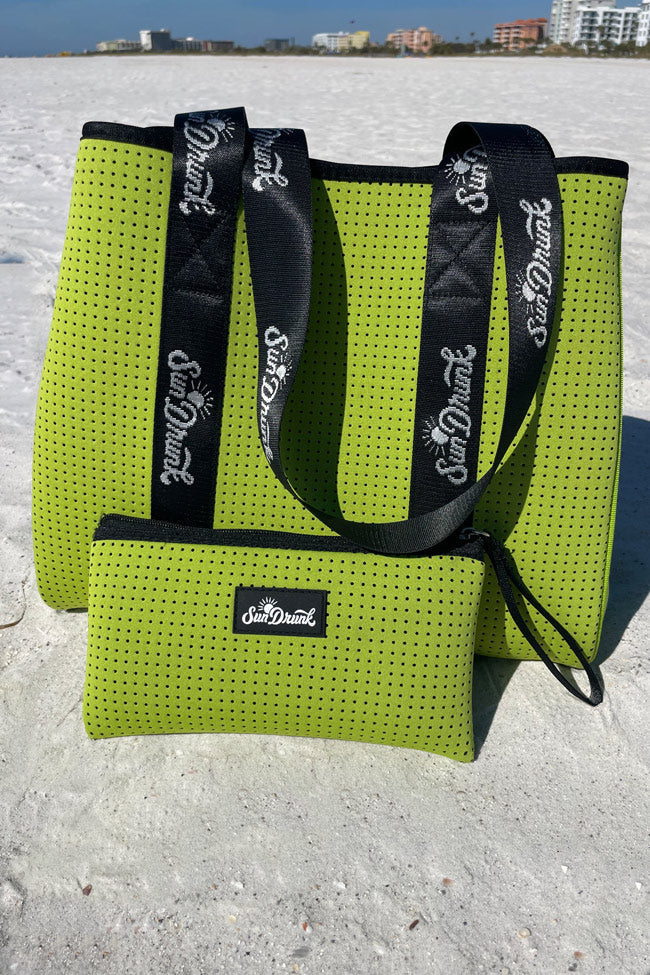 Green mesh bags with black straps on a sandy surface