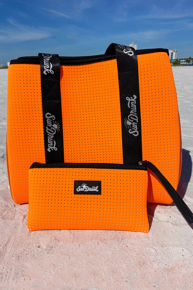 Orange textured bag with black straps and 'Sun & Dew' branding on a sandy background.