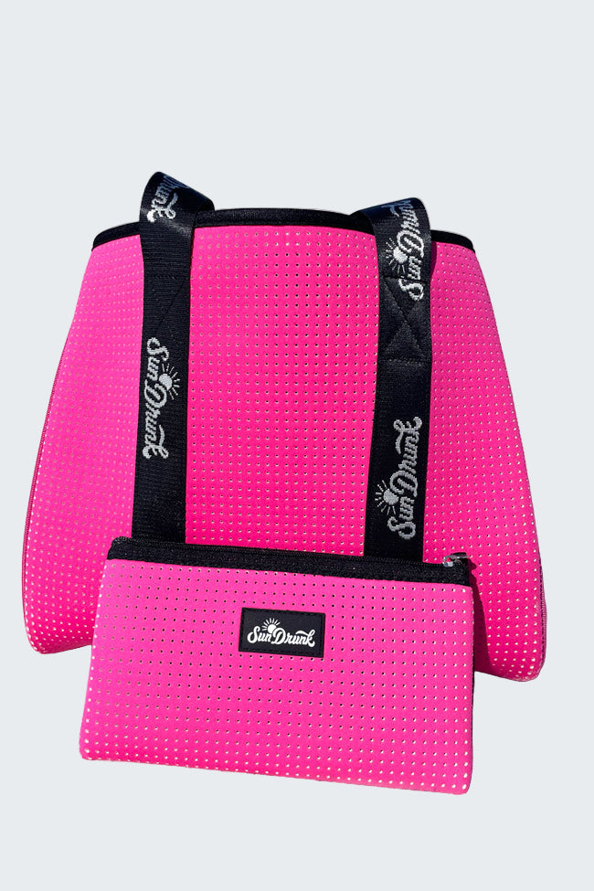 Pink textured bag with black straps and 'Sun Dune' logo on a sandy beach.