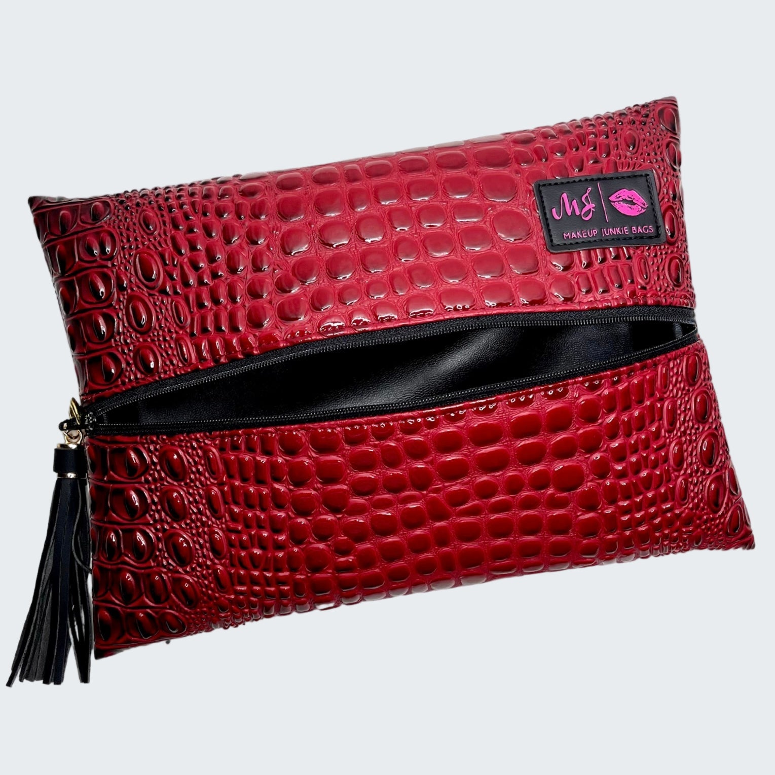 Red crocodile-patterned clutch bag with a visible brand label on a white background