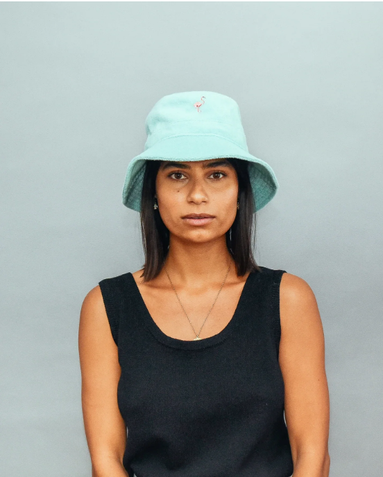 Person wearing a light blue bucket hat against a gray background