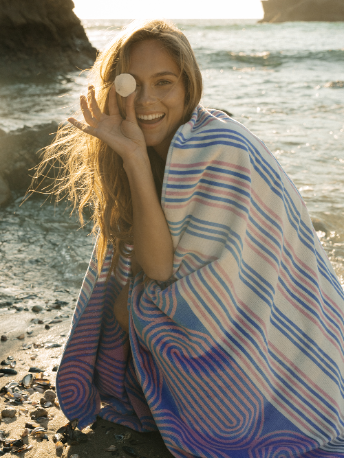 Woman wrapped in a colorful striped towel on a beach