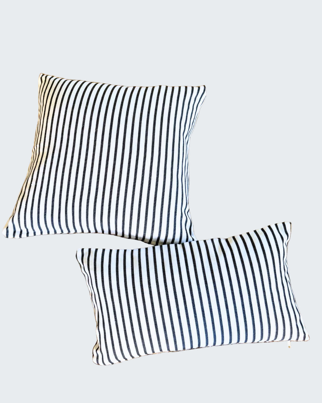 Two black and white striped pillows on a woven mat.