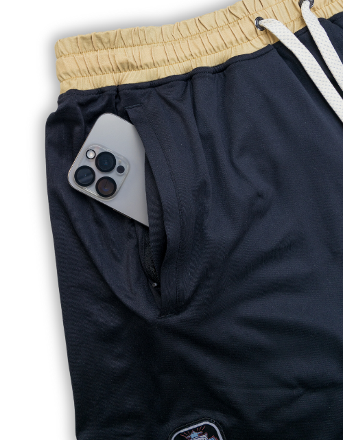 Navy blue sweatpants with beige waistband and white drawstrings, featuring a phone inside.
