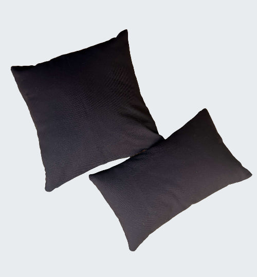 Two black pillows on a textured beige surface