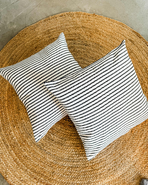 Two striped pillows on a woven mat