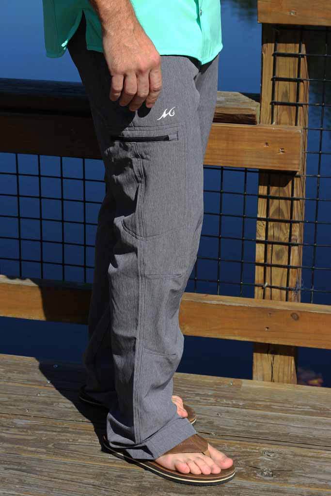 Person wearing gray pants with a brand logo, standing on a wooden deck.