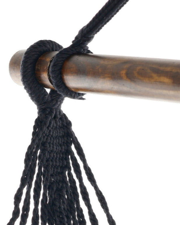 Close-up of a black cord tied around a wooden rod on a white background