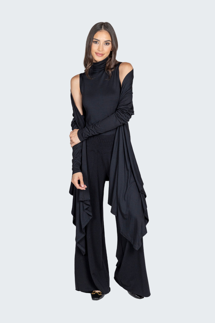 Woman wearing a black outfit with ruffled details on a gray background