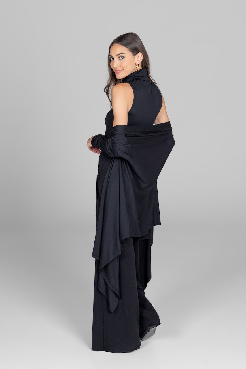 Woman wearing a black evening gown with a draped design on a gray background