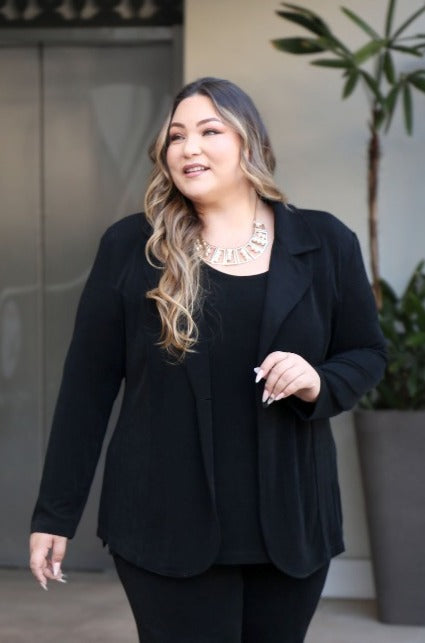 Woman wearing a black blazer in an indoor setting with plants.
