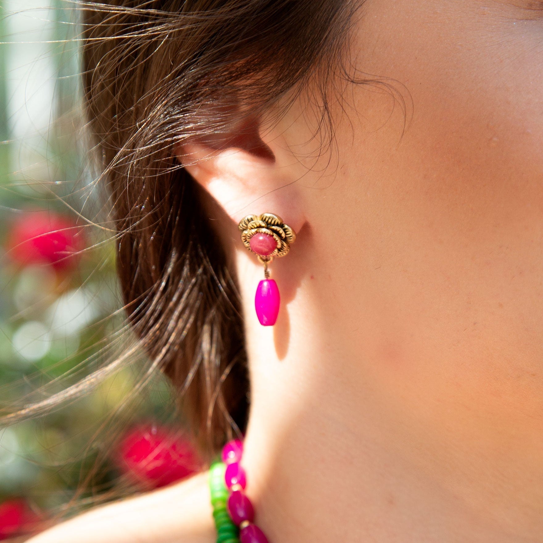 Close-up of a person wearing pink earrings with a blurred background