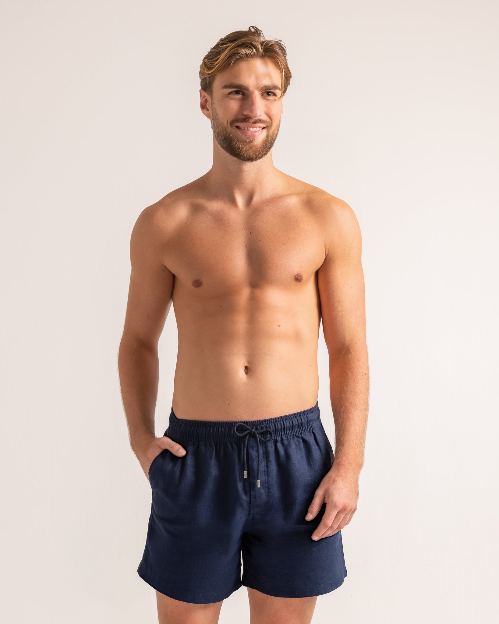 Man wearing navy blue swim shorts against a plain background
