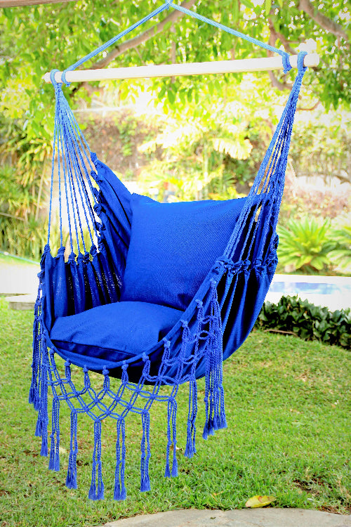 Blue hammock chair with cushions hanging outdoors on a sunny day.