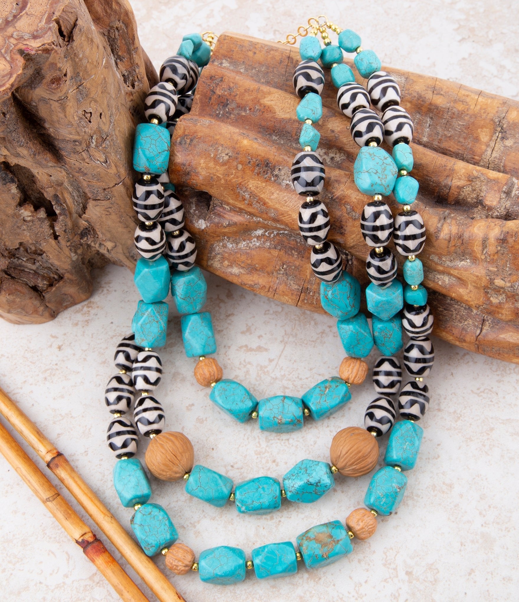 Turquoise beaded necklace with black and white patterned beads on a wooden surface
