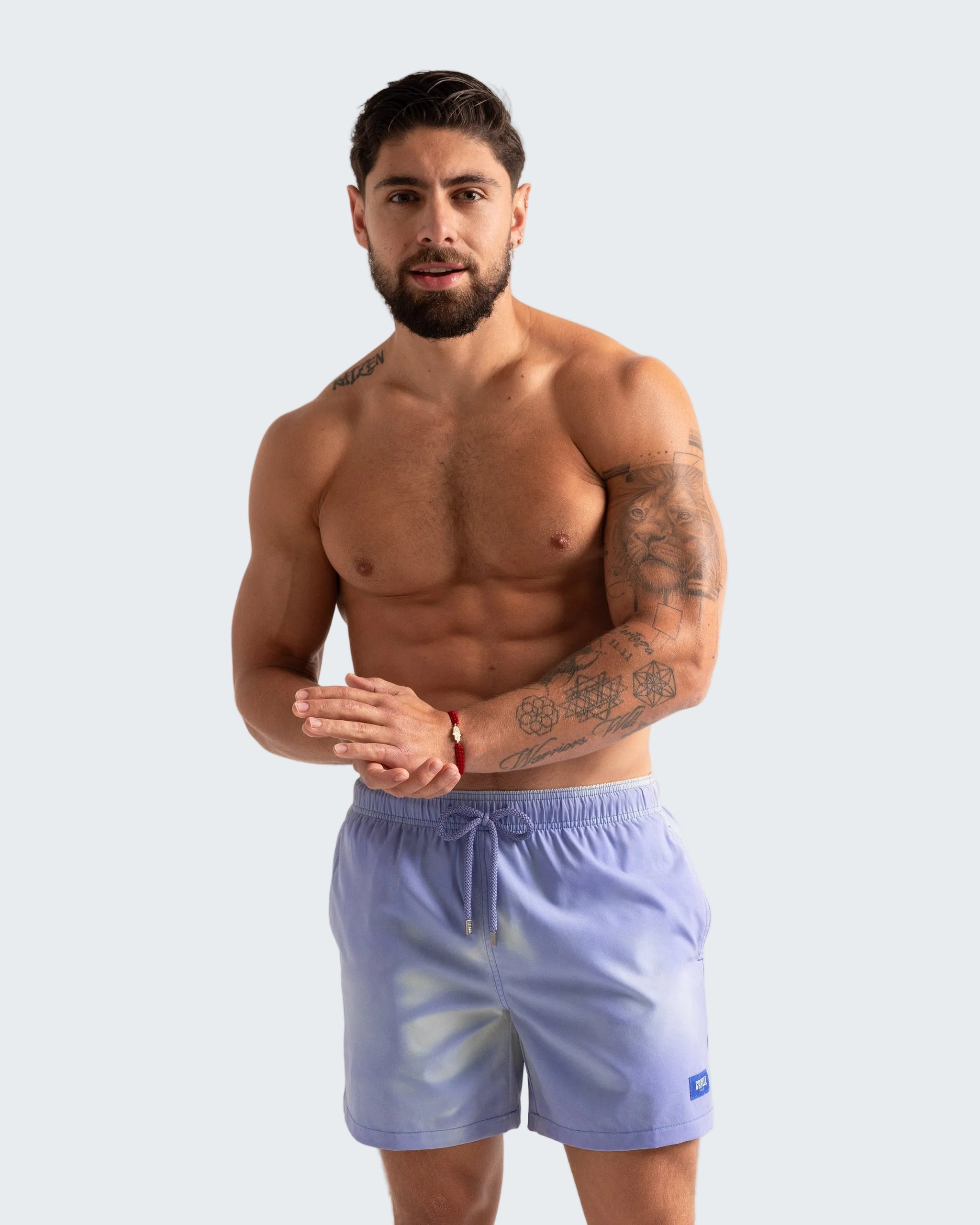 Man wearing light blue swim shorts on a plain background