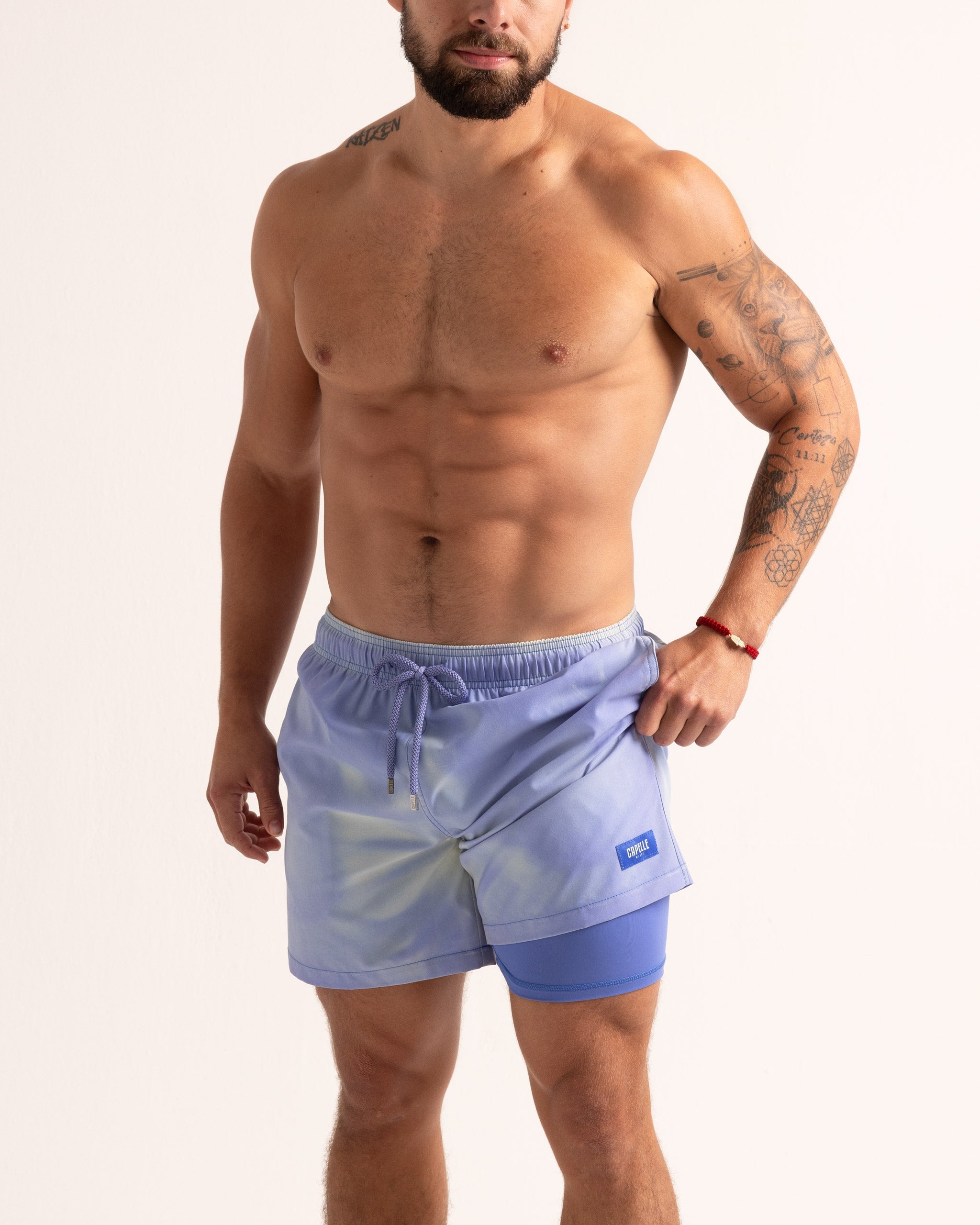 Man wearing light blue swim shorts on a plain background