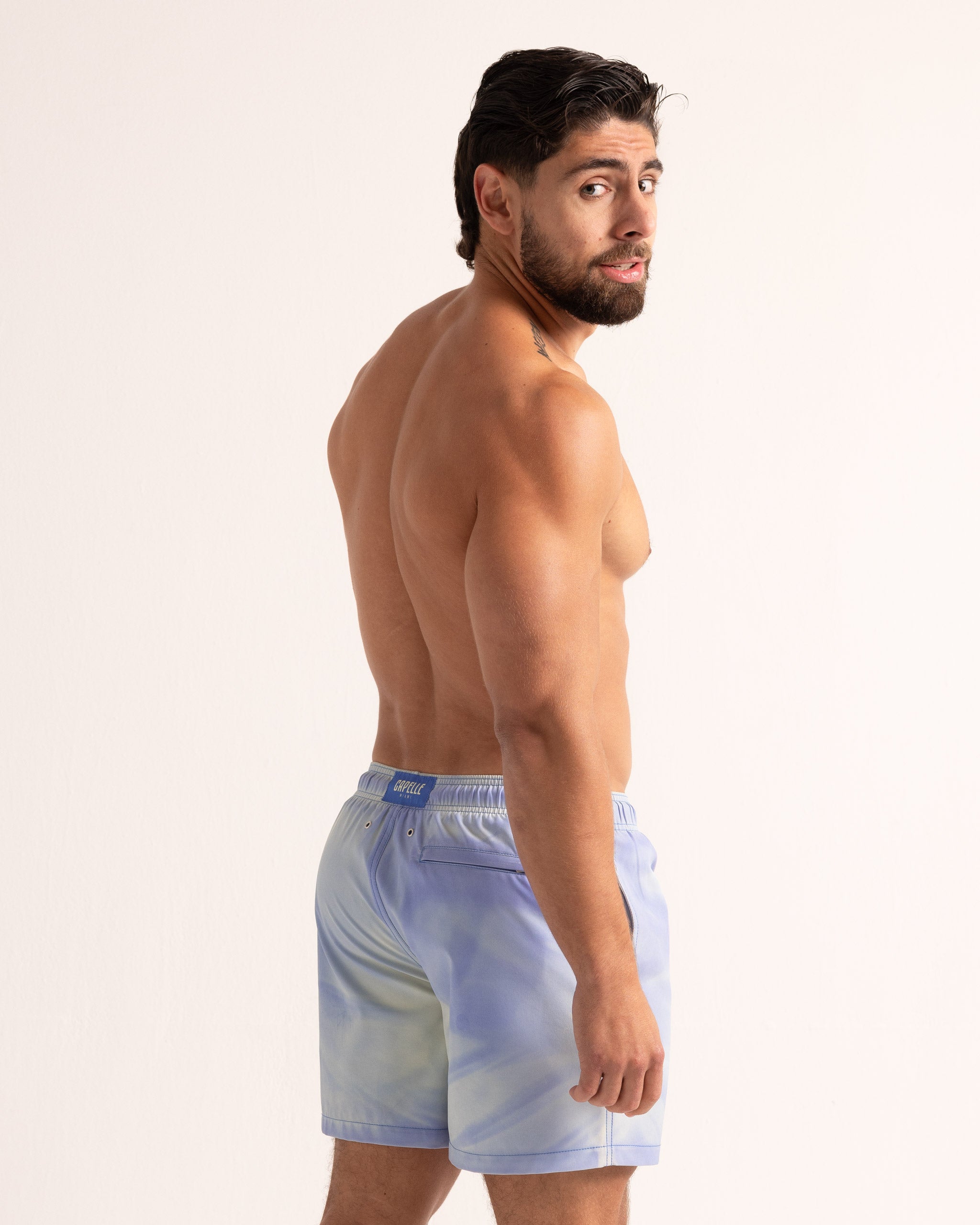 Man wearing tie-dye swim shorts on a white background