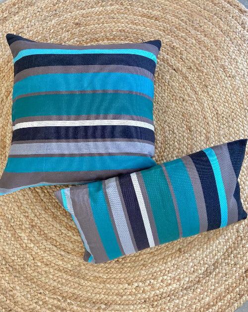 Two striped pillows on a woven surface