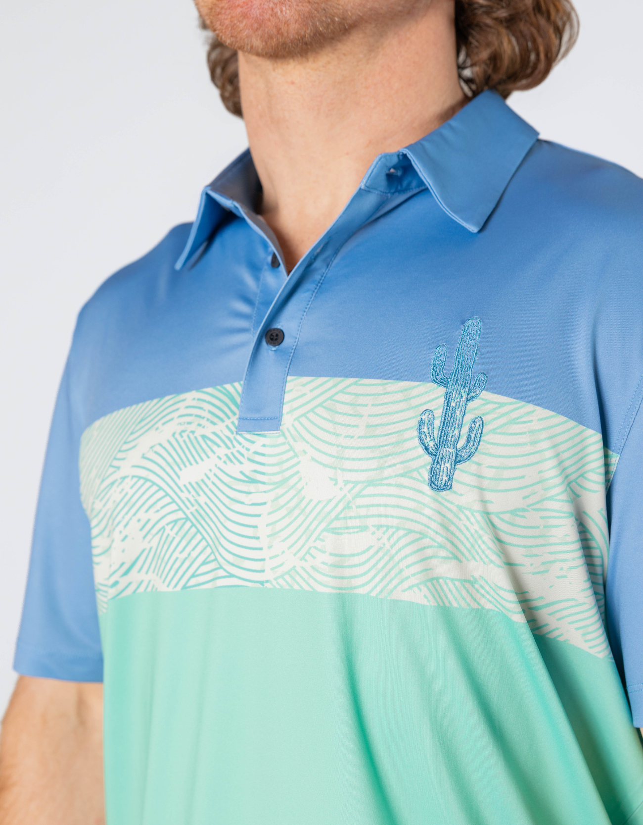 Blue and green polo shirt with cactus design on a white background