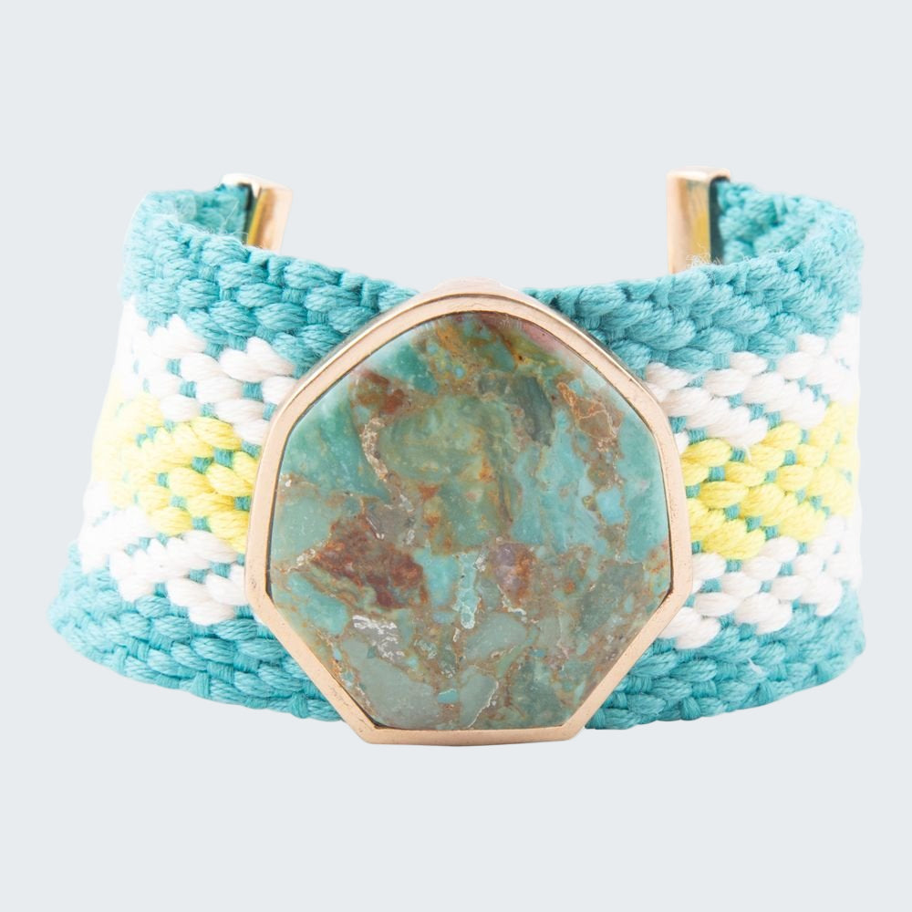 Turquoise woven bracelet with a stone-like center on a white background