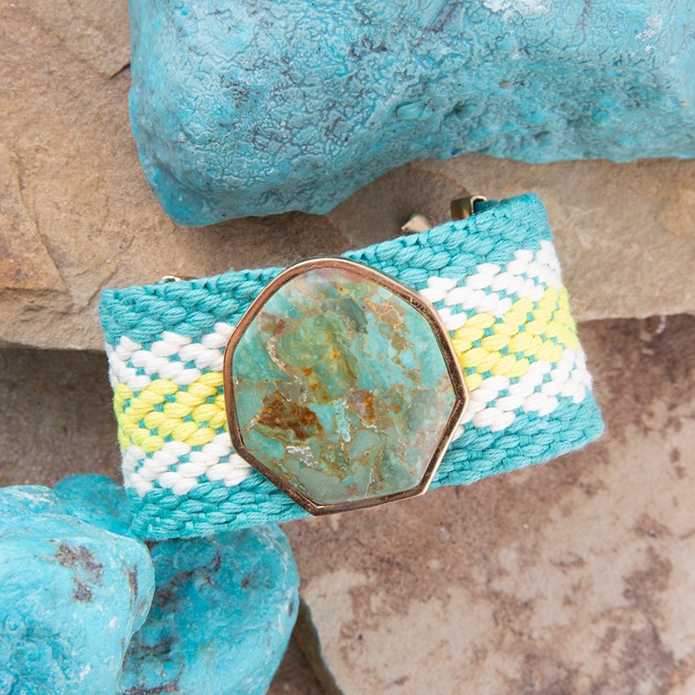 Turquoise woven bracelet with a geometric stone clasp on a stone surface