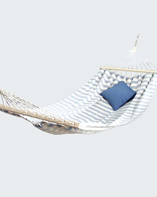 Hammock with a blue pillow on a stone patio by a poolside