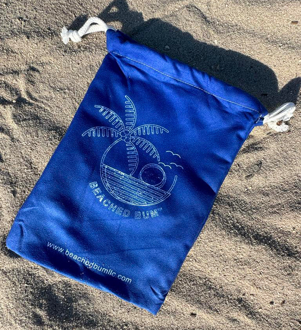 Blue drawstring bag with a logo and text on a sandy surface