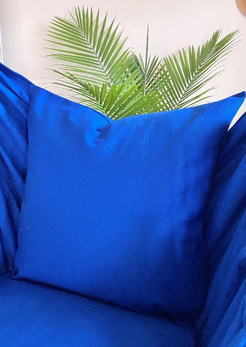 Blue pillow with palm leaf design on a white background