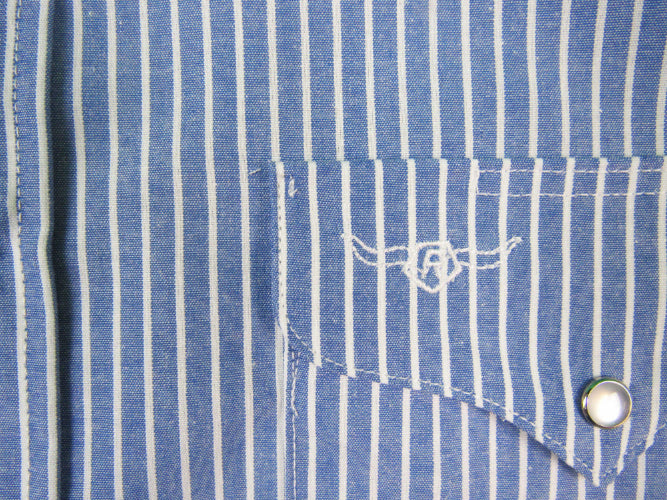 Close-up of a blue and white striped shirt pocket with a brand logo.