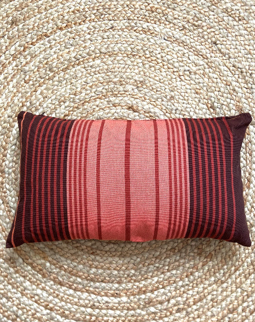 Striped red and brown pillow on a textured beige surface