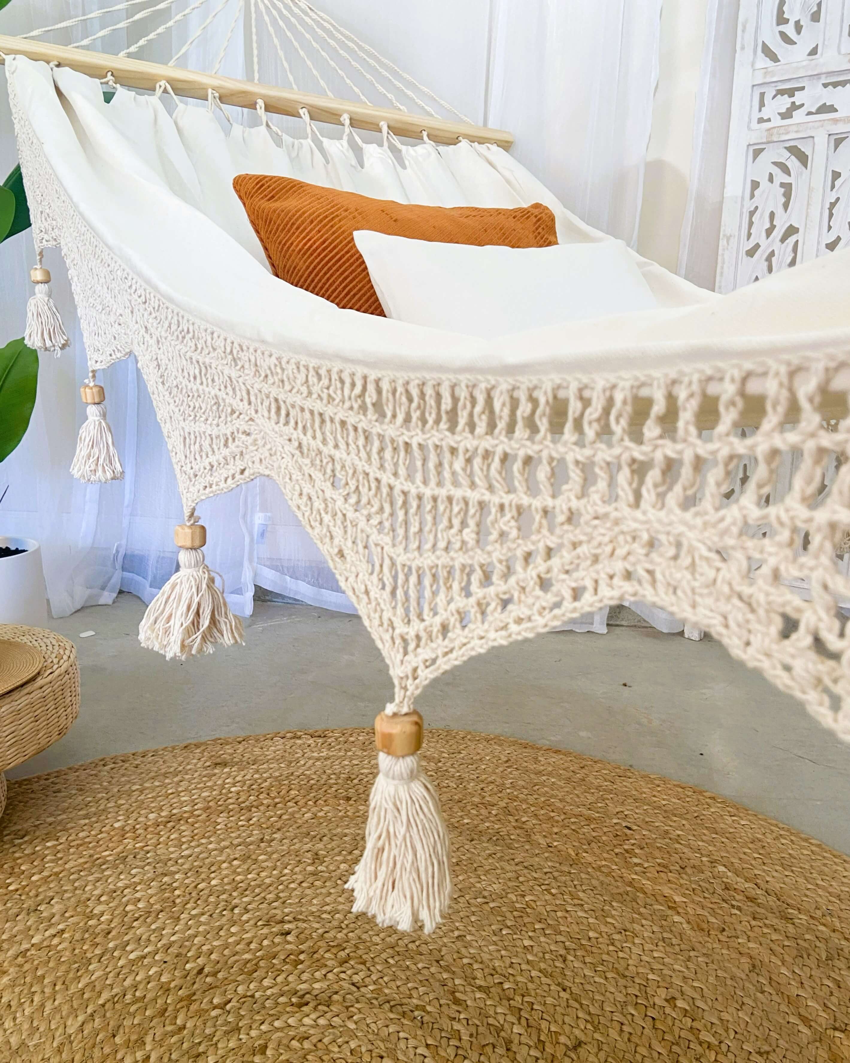 Macrame hammock with wooden beads and tassels in a room setting.