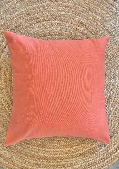 Coral pillow on a textured woven surface