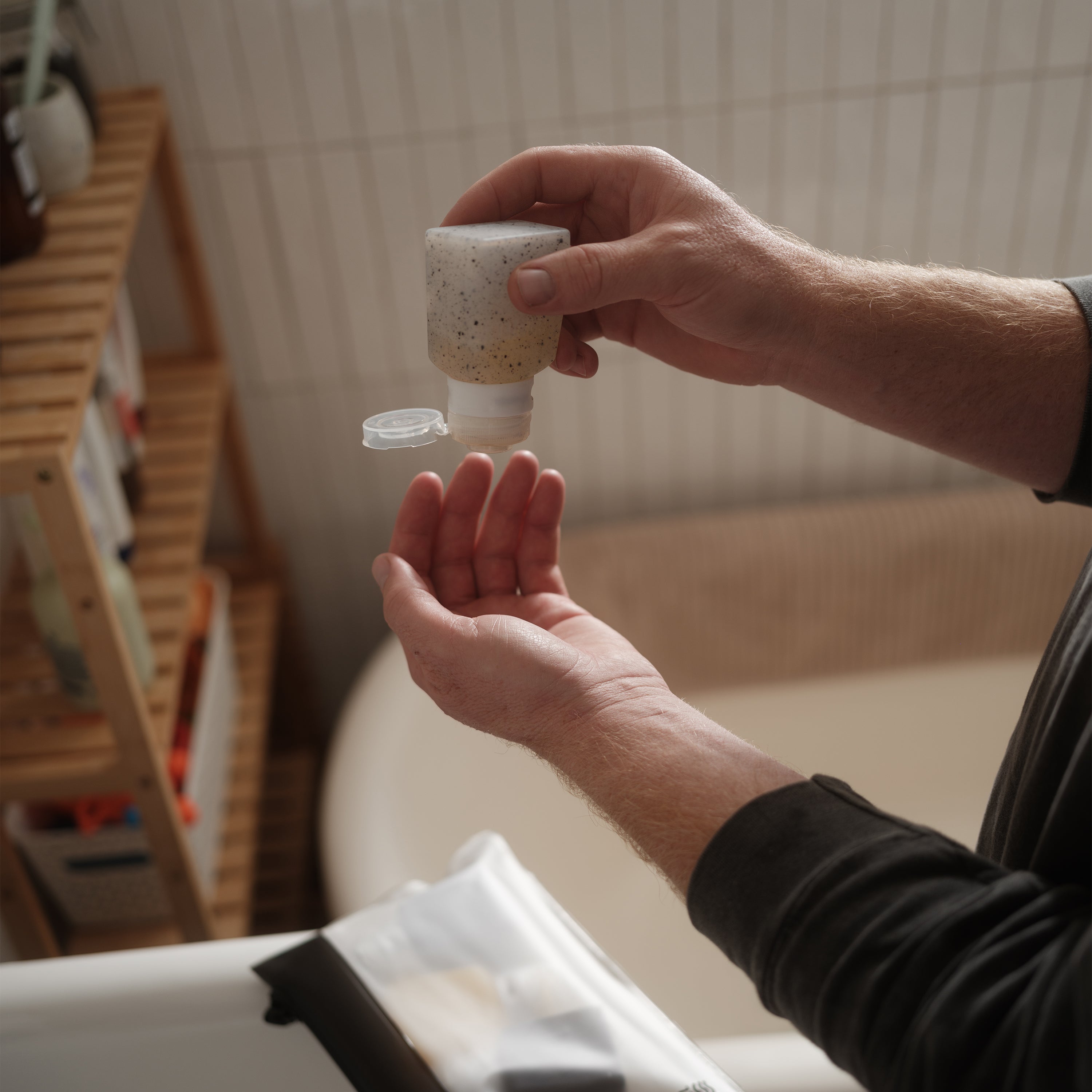 Person holding a small container over another hand in an indoor setting