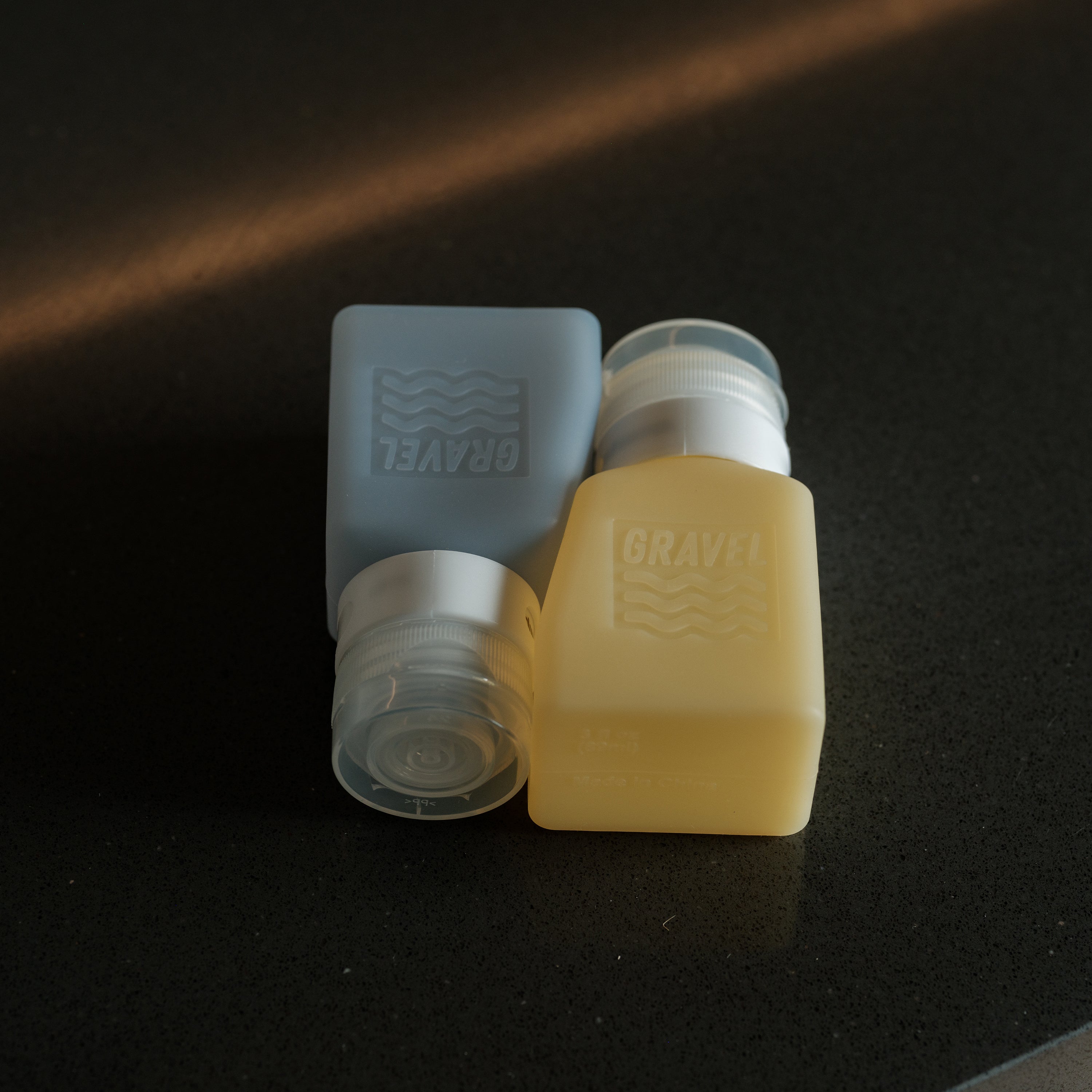 Two plastic containers with 'GRAVEL' branding on a dark surface