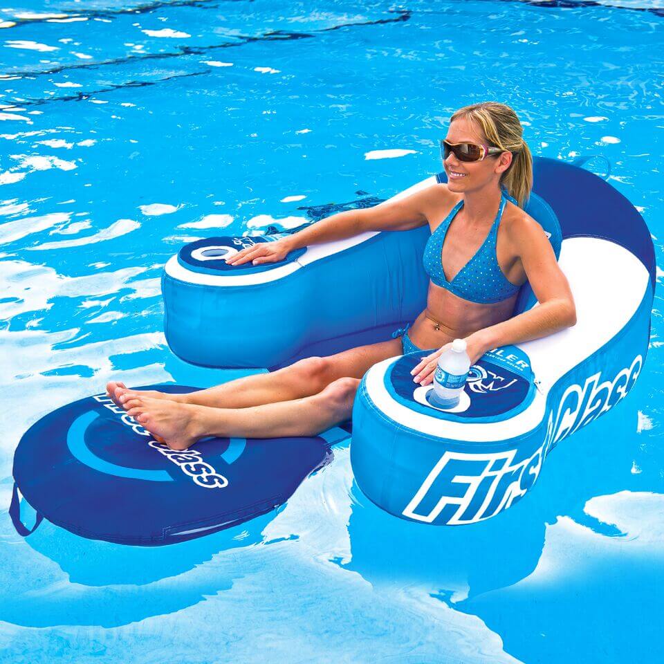Woman lounging on a blue inflatable pool float with a cooler, surrounded by clear blue water.